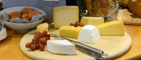 A cheese board with various cheeses, grapes, and a sign indicating a cheese selection.