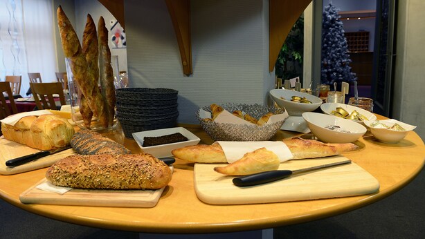 A table with various breads and pastries, a cutting board, and a knife.