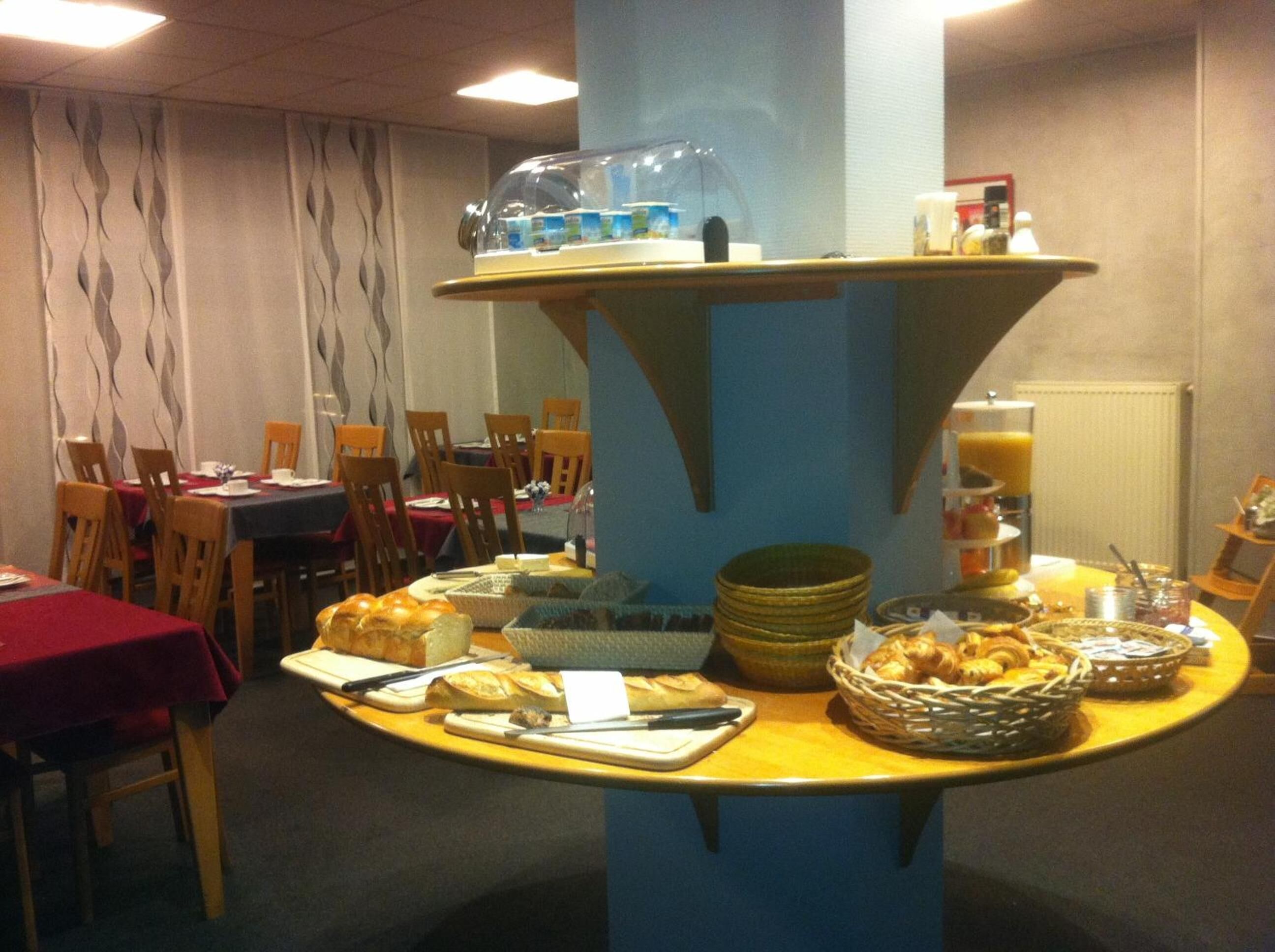A breakfast buffet setup with bread, pastries, and beverages.
