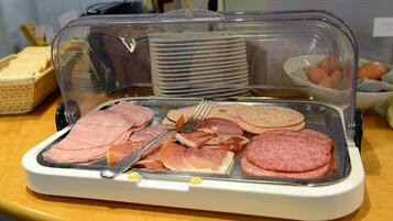 Ein Frühstücksbuffet mit verschiedenen Fleischsorten und Eiern.