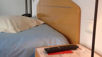 A hotel room with a bed, a bedside table, a lamp, and a remote control.