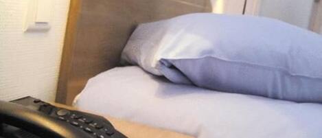 Une chambre d’hôtel avec un lit, un téléphone sur la table de chevet et une lampe.