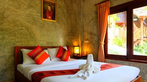 Una cama bien hecha con ropa de cama blanca y detalles rojos, un cuadro en la pared y una ventana con cortinas.