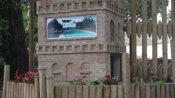 A stone structure with a sign advertising 'Colle sul Lago' and 'Agritourism'.