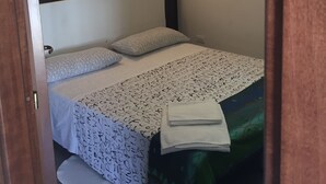 A small, neatly made bed with patterned bedding, a bedside table, and a wall-mounted light fixture. - Colle Sul Lago (Cingoli)