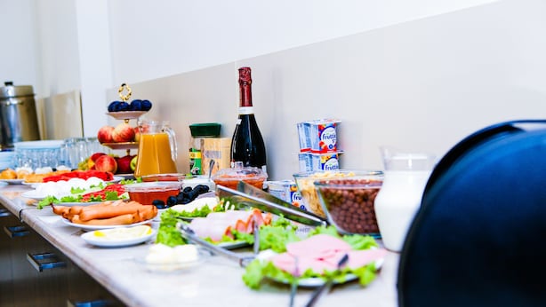 A buffet table with various food items, including fruits, vegetables, and hot dogs. - Hotel Rio (Tbilisi)