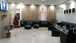 A modern living room with a large flat-screen TV, a Christmas tree, and a sofa set. - Hotel Rio (Tbilisi)