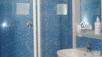 A bathroom with a glass-enclosed shower, a white sink, and blue-tiled walls.