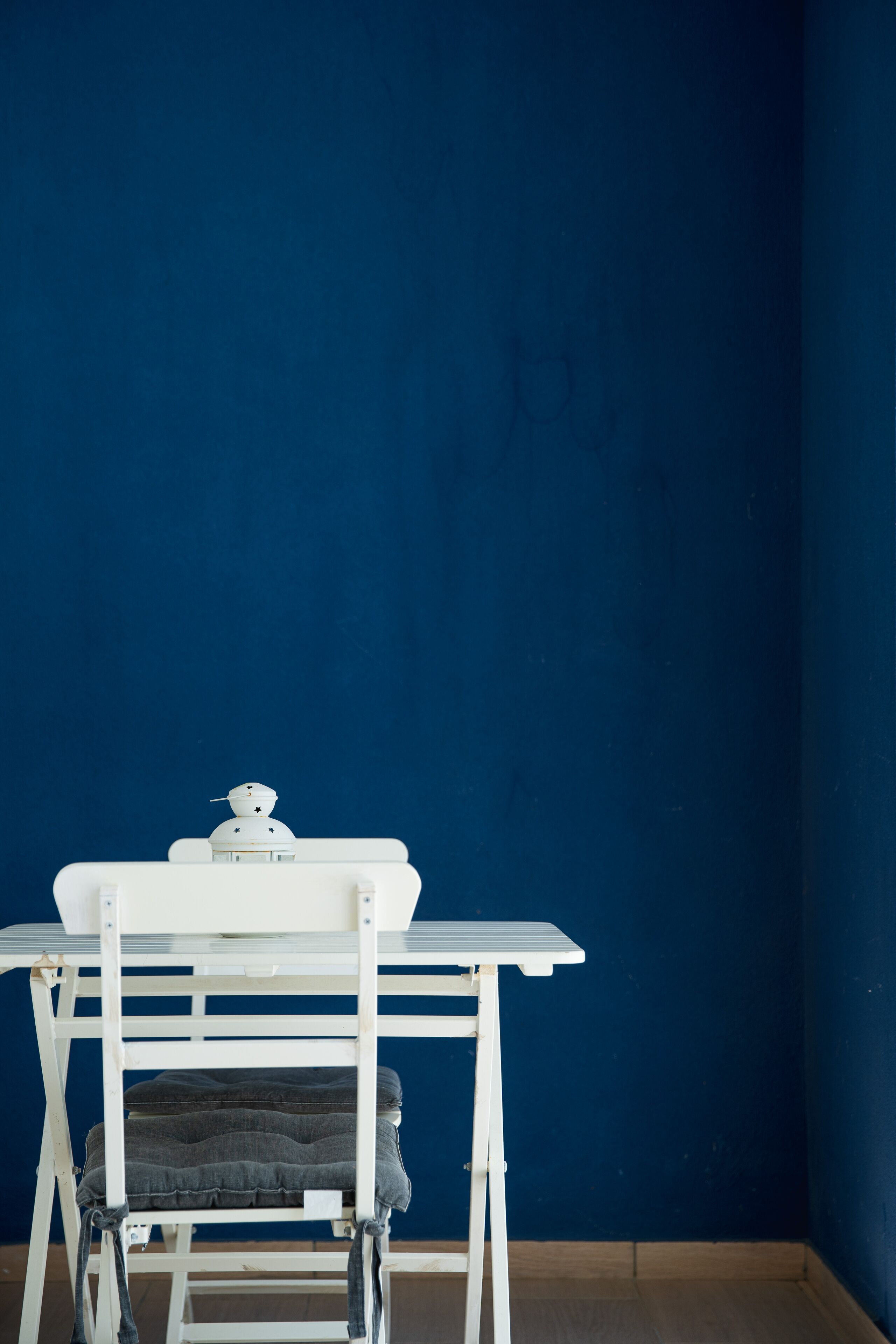 A white table with a chair against a blue wall.