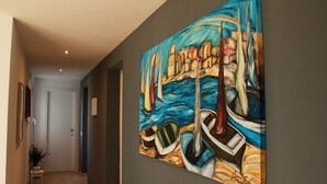 A hallway with a large painting of boats on a wall. - Casa Azul (Alcamo)