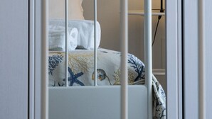 A white metal bed frame with a decorative headboard, a white wall, and a bedside lamp. - Casa Azul (Alcamo)