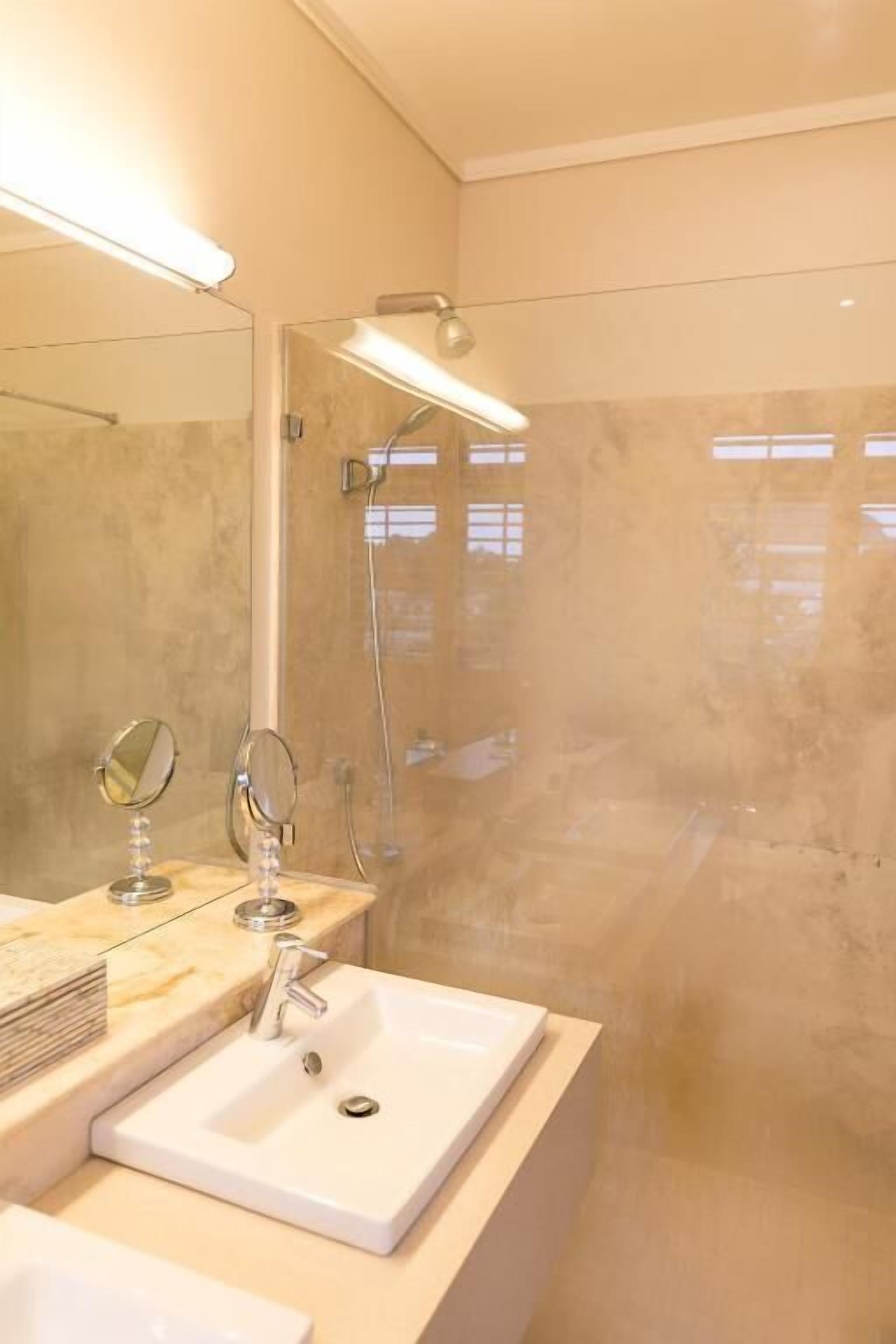 A modern bathroom with a large mirror, a sink, and a shower area.