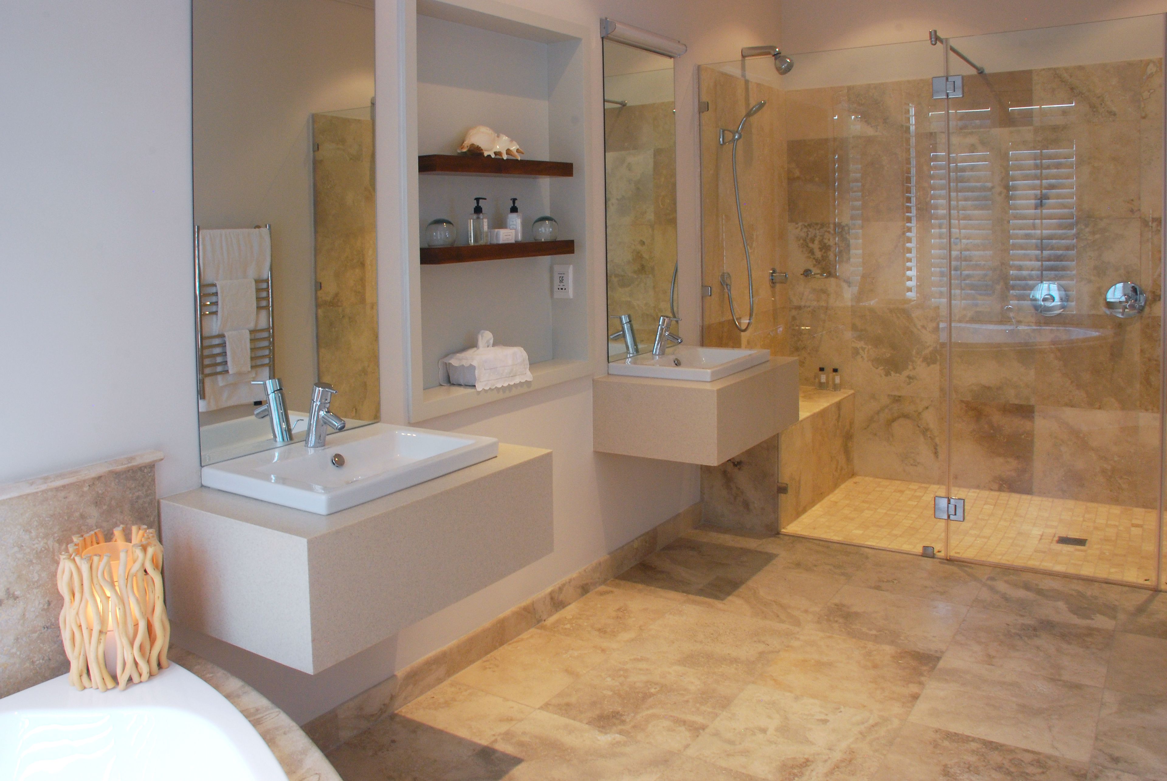 A modern bathroom with two sinks, a glass-enclosed shower, and a vanity with shelves.