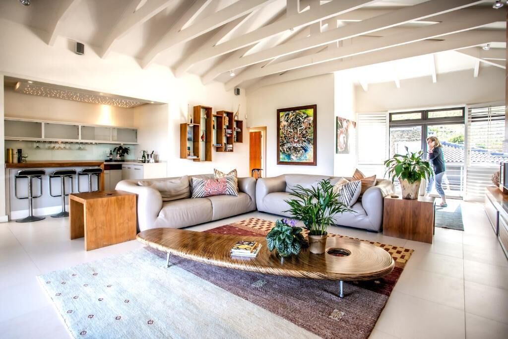 A modern living room with a sectional sofa, a coffee table, and a kitchen area with bar stools.
