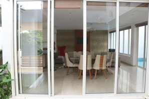 A modern interior with a dining area featuring a glass partition, a sofa, and a red pillow.