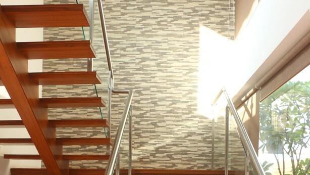 Un escalier moderne avec des marches en bois et des rampes en métal, menant à l’étage supérieur.