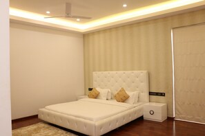 A bedroom with a large bed, a nightstand, a ceiling fan, and a window with curtains.