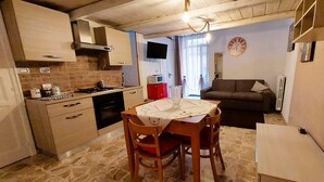 Una cocina compacta con comedor, un televisor montado en la pared y un reloj en la pared.