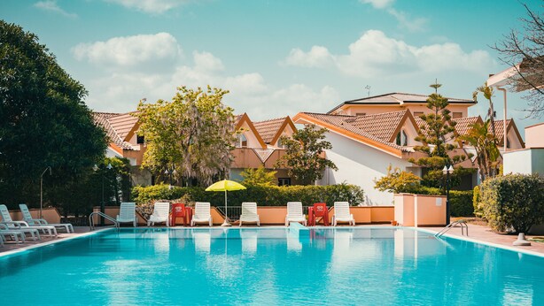 A swimming pool with lounge chairs and a yellow umbrella.