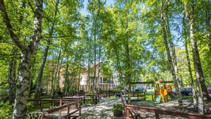 Un parque con bancos de madera, un área de juegos y un edificio al fondo.