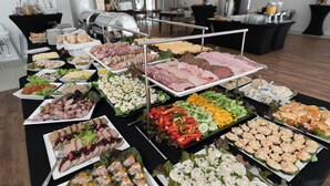 Un bufé con diferentes opciones de comida, incluyendo carnes, quesos y ensaladas.