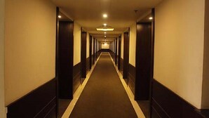 A long, narrow hotel corridor with a carpeted floor and a series of doors on either side. - Hotel Grand Meridian (Katni)