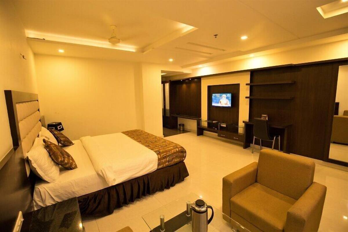 Ein Hotelzimmer mit Bett, Fernseher, Sitzecke und Couchtisch.