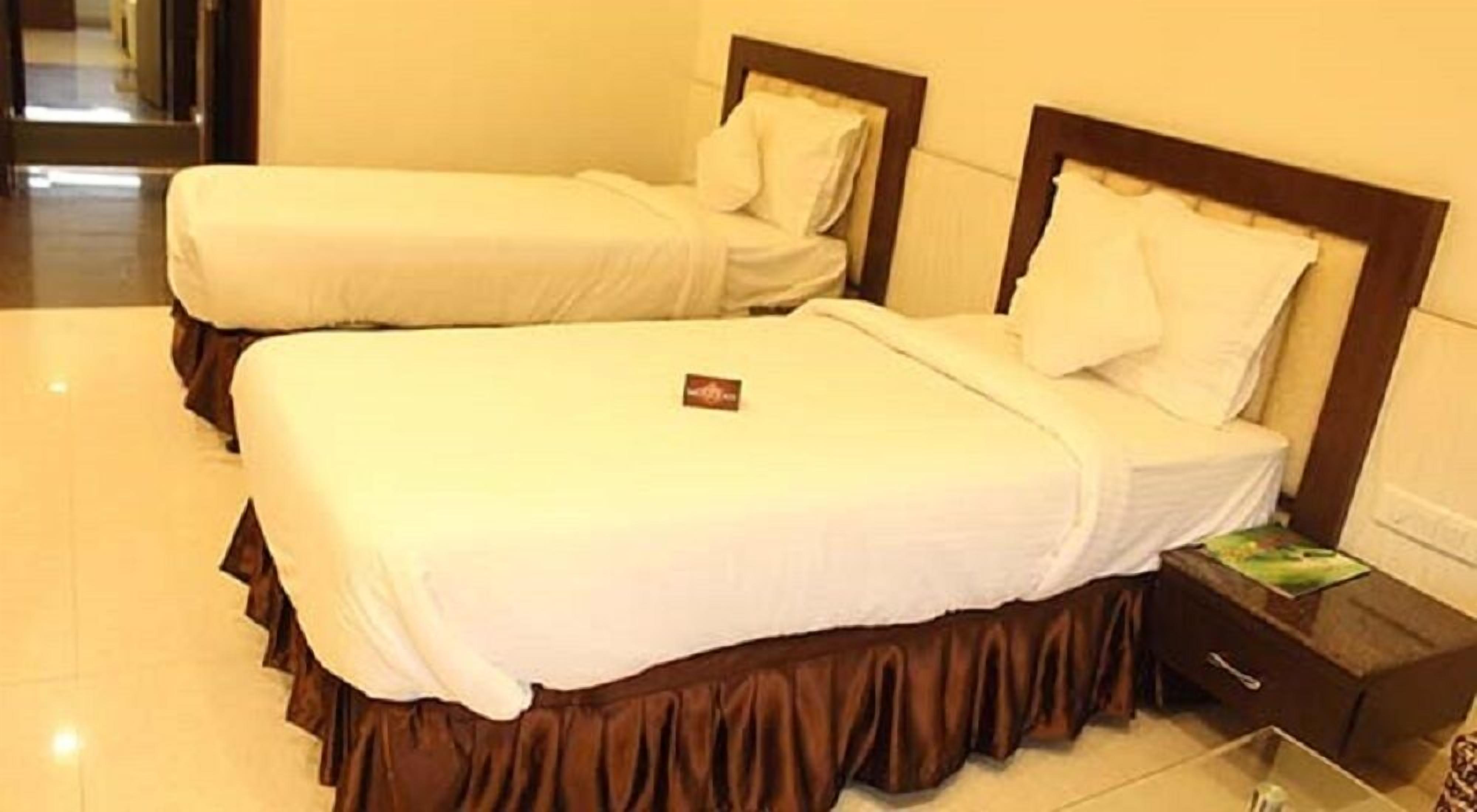 Two single beds with wooden headboards and white bedding in a hotel room.