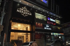 Un hotel con un letrero llamativo que dice 'Hotel Grand Meridian' y un letrero de 'City Mall' encima.
