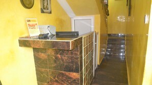 A reception desk with a marble counter, a clock on the wall, and a staircase leading to another floor. - Mac Dove Lounge & Suites ltd (Lagos)