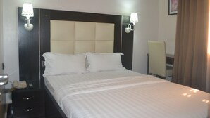 A hotel room with a large bed, two bedside lamps, a chair, and a bedside telephone. - Mac Dove Lounge & Suites ltd (Lagos)