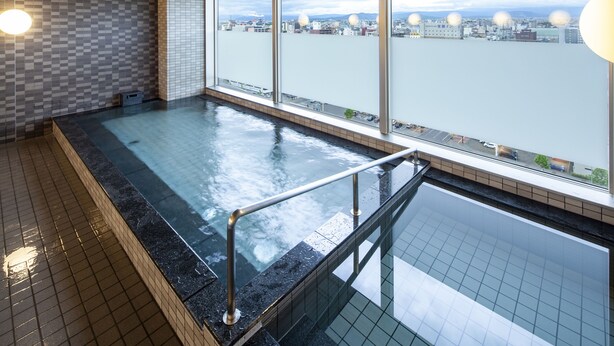 A modern indoor swimming pool with a view of a cityscape through large windows.