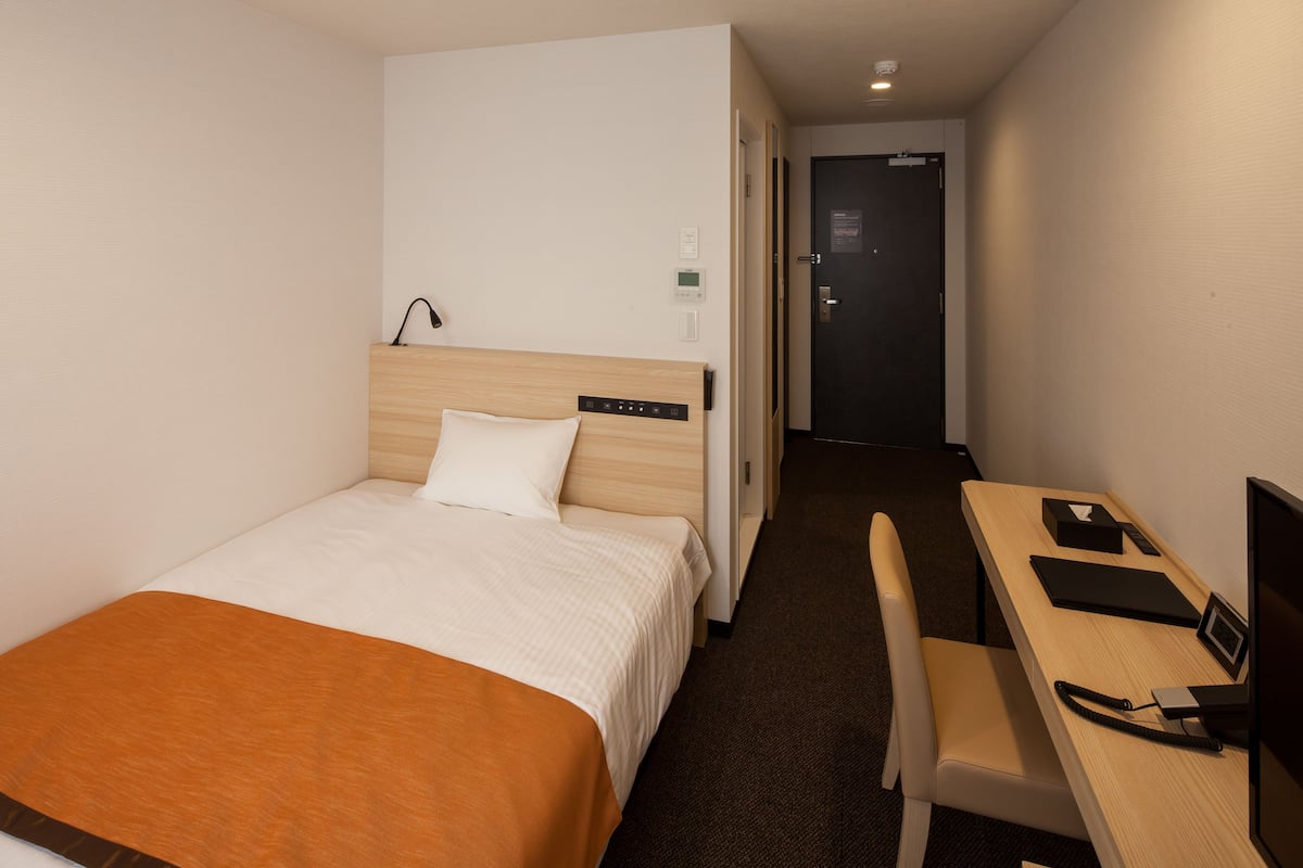 Una habitación de hotel con una cama, un escritorio y una silla.