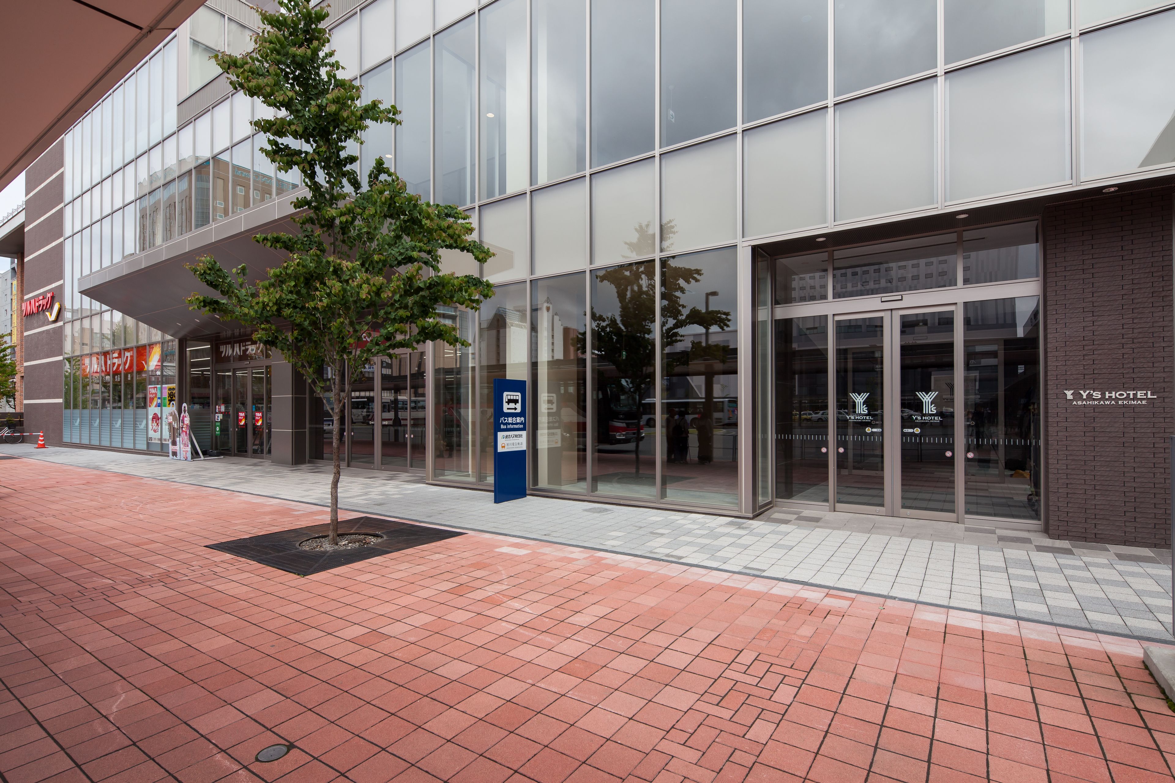 A modern building with large glass windows, a brick facade, and a tiled walkway.