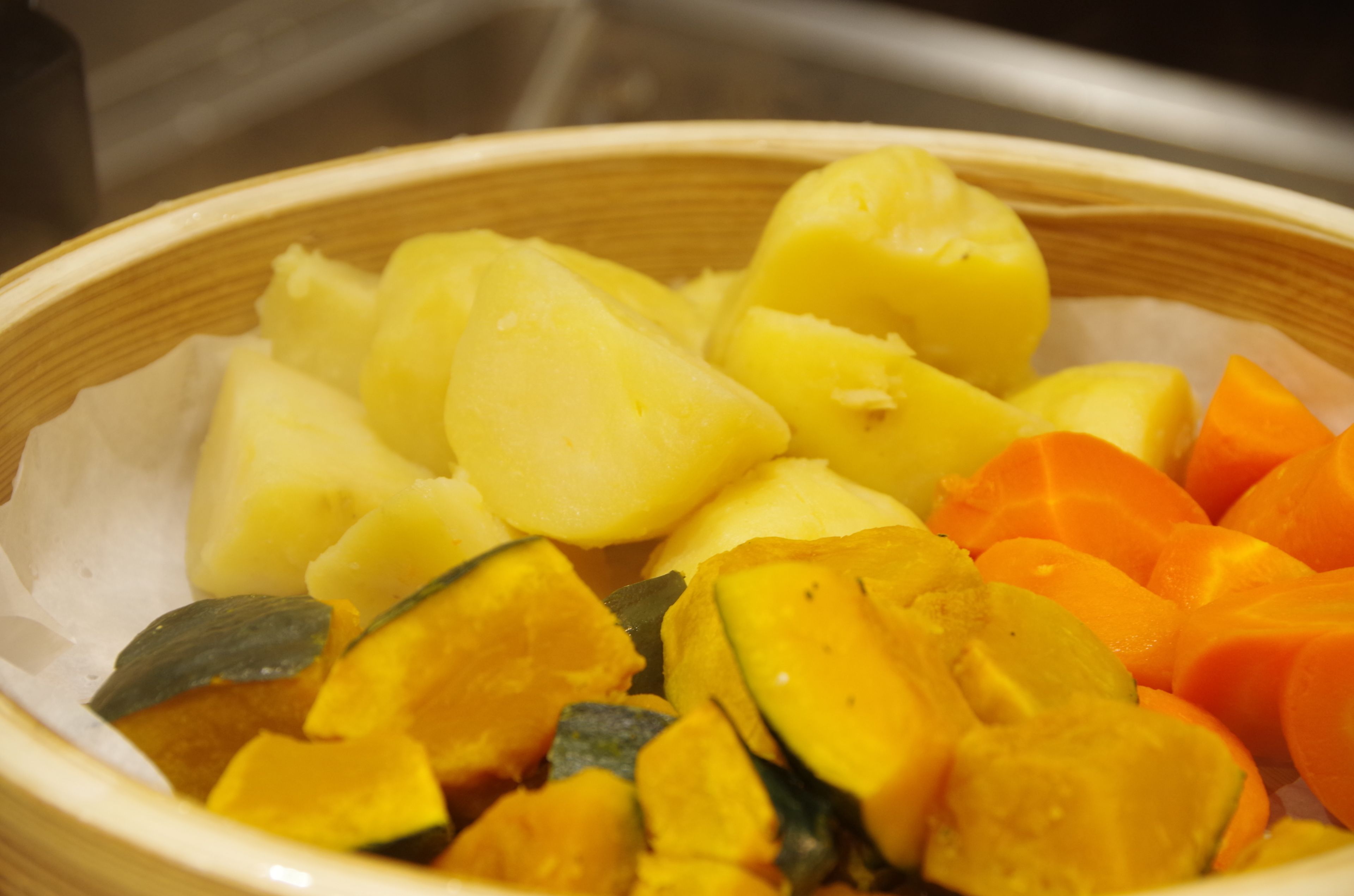 A bowl containing sliced yellow and orange fruits, possibly mango and papaya.