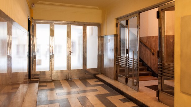 A hallway with a tiled floor, a set of double doors with frosted glass panels, and a staircase with metal railings. - Stunning Design Apartment (Prague)