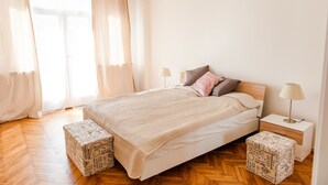 A bedroom with a bed, two bedside tables, a nightstand, and a window with curtains. - Stunning Design Apartment (Prague)