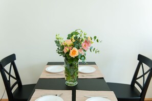 Una mesa de comedor con un florero, dos sillas y un mantel individual.
