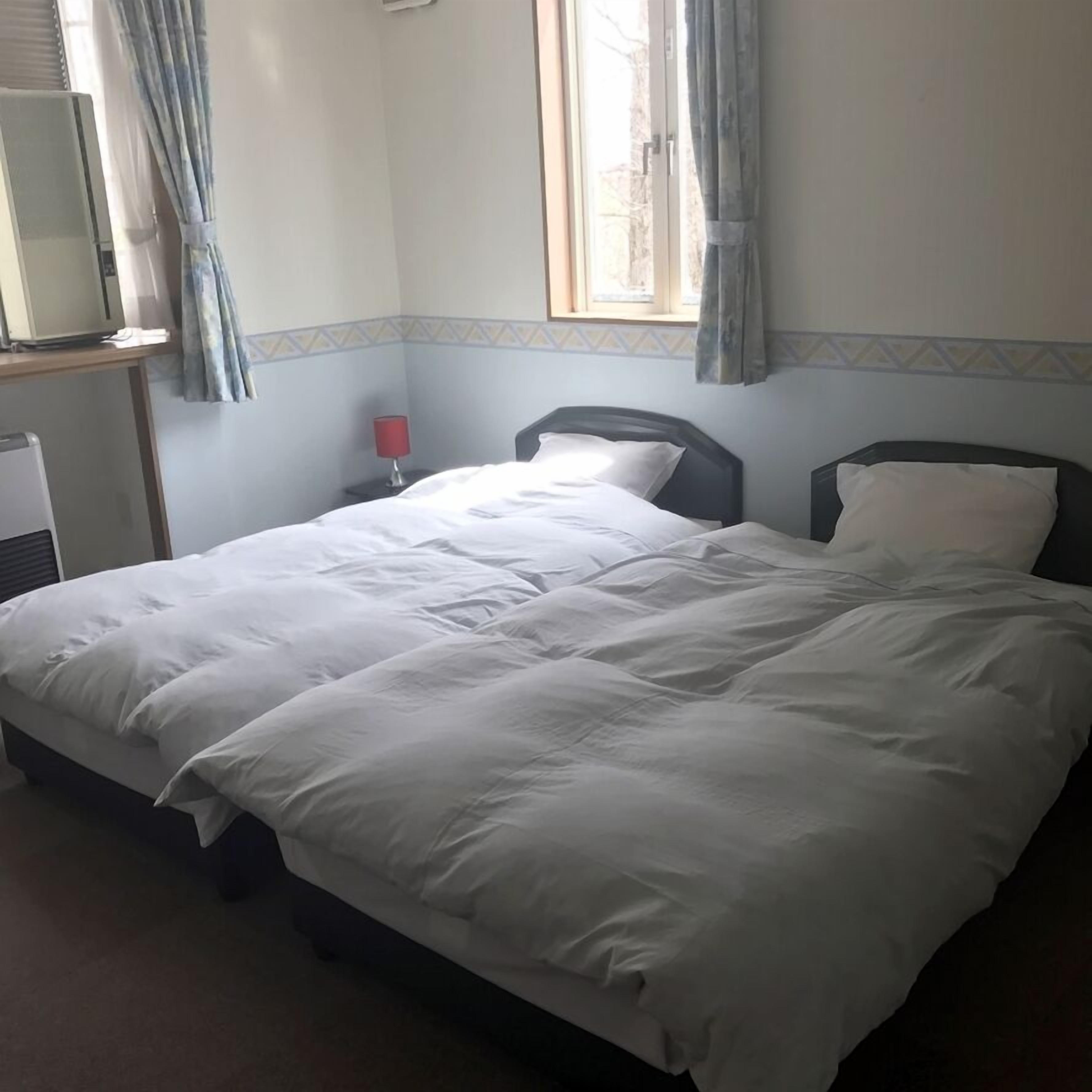 A hotel room with a bed, a desk with a computer, a window with curtains, and a wall with a decorative border.