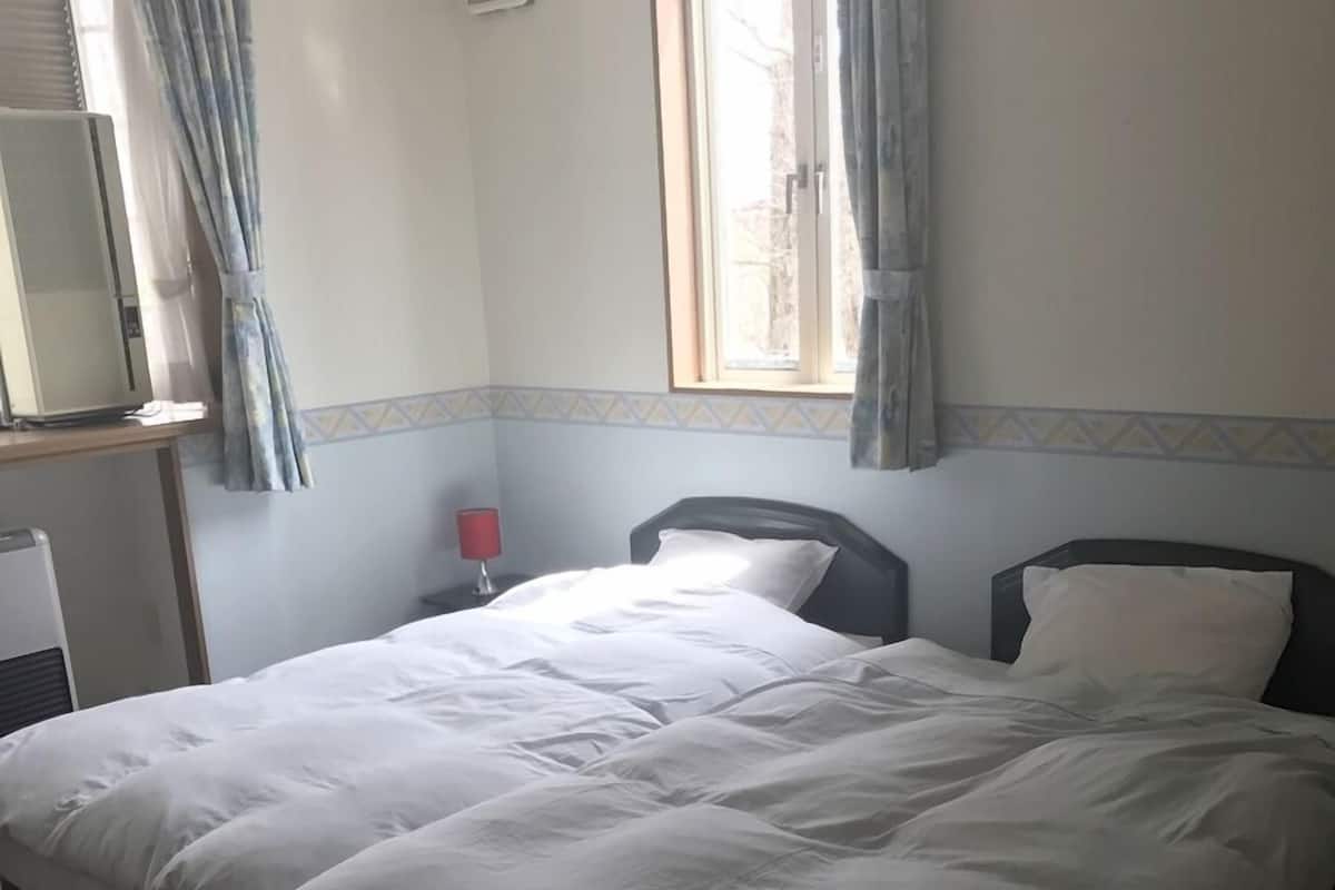 Ein Hotelzimmer mit einem Bett, einem Schreibtisch mit Computer, einem Fenster mit Vorhängen und einer Wand mit dekorativem Zierstreifen.