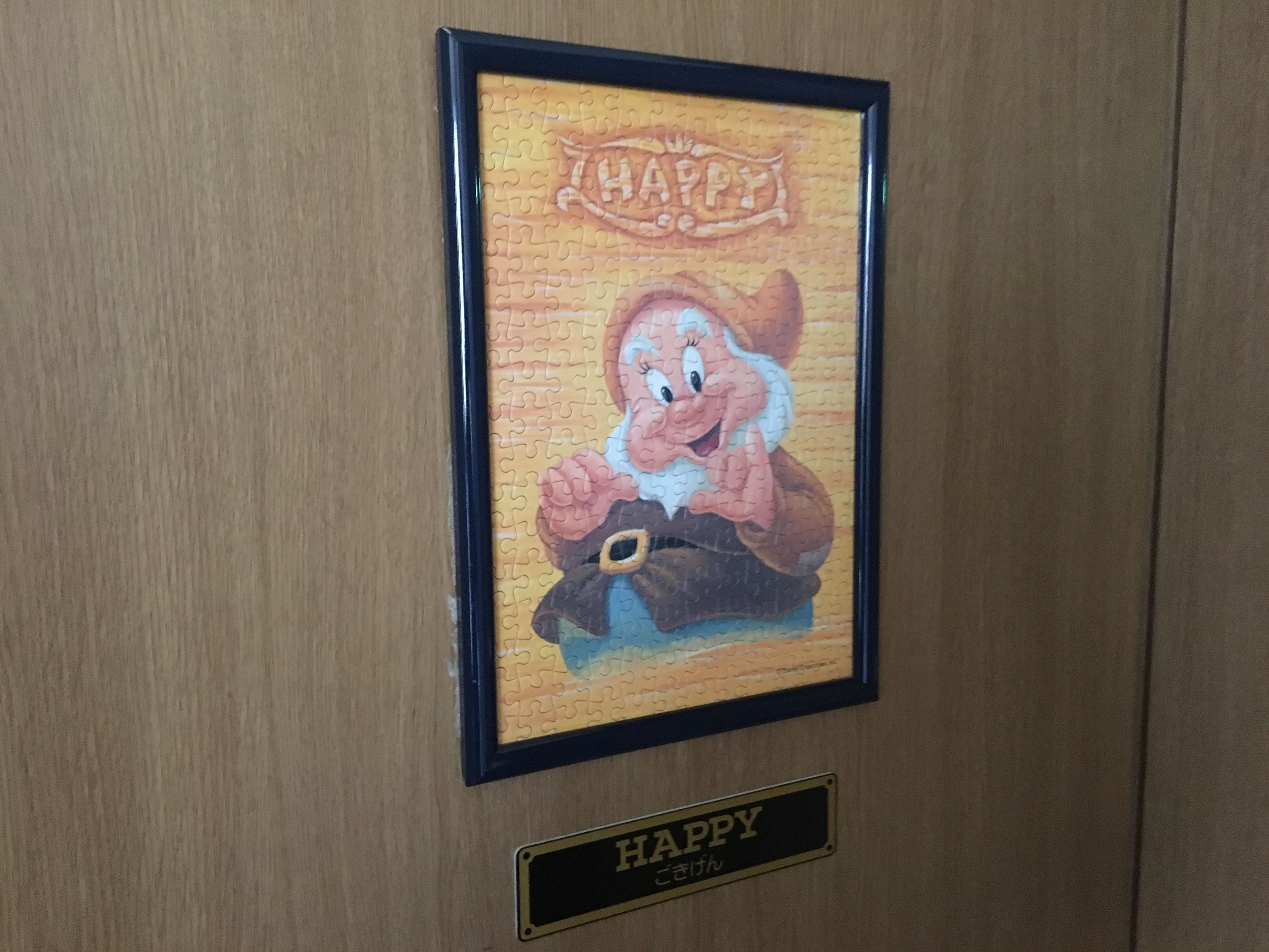 A framed picture of a cartoon character with the word "HAPPY" above it, and a plaque below with the word "HAPPY".