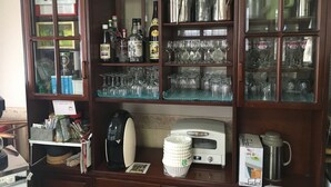 A kitchenette with a coffee maker, sugar packets, and a coffee pot.