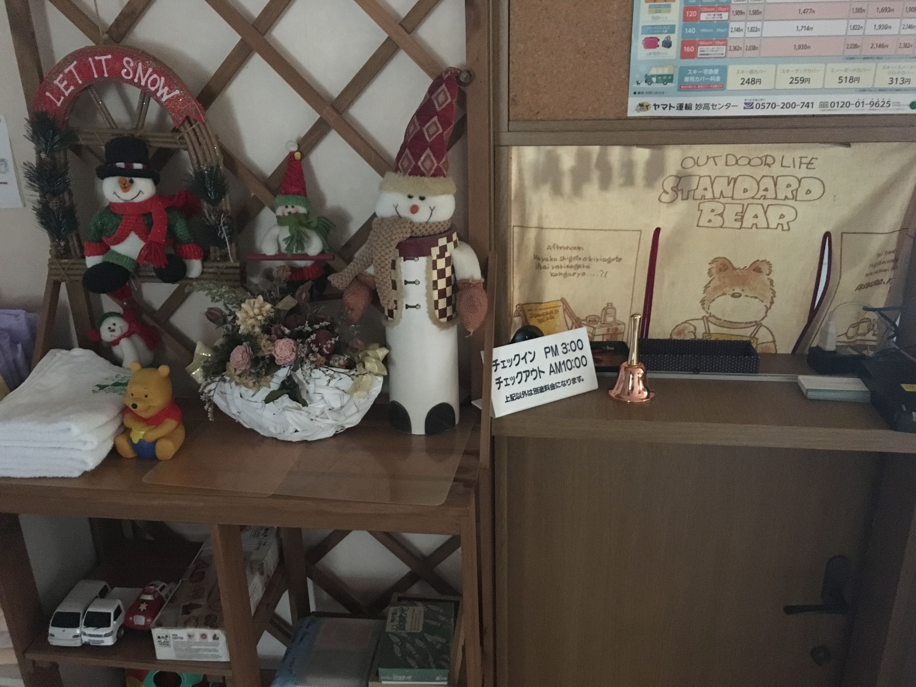 Una exhibición con un muñeco de nieve, un osito de peluche y un cartel que muestra los horarios de registro.