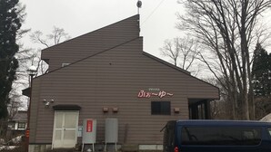 A building with a sloped roof, a satellite dish, and a sign with Japanese characters.