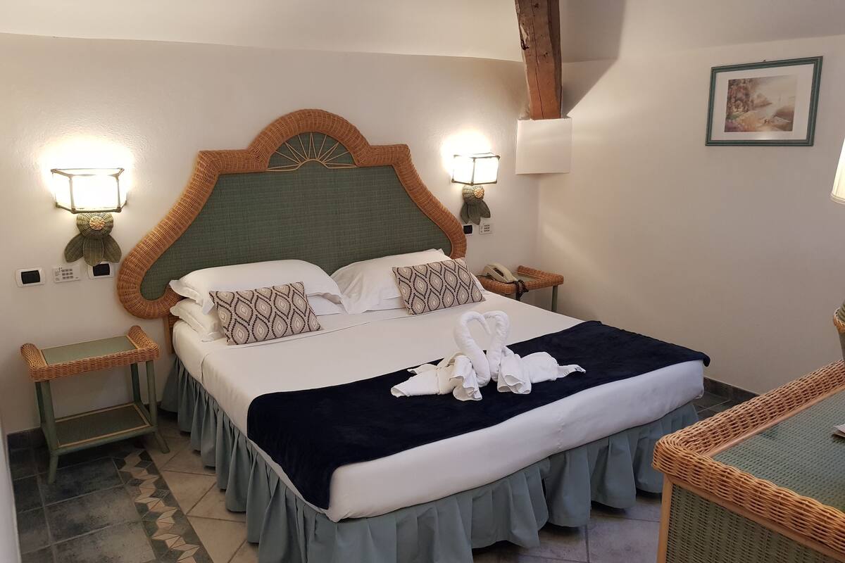 A neatly made bed with a green headboard, two bedside lamps, and a framed picture on the wall.