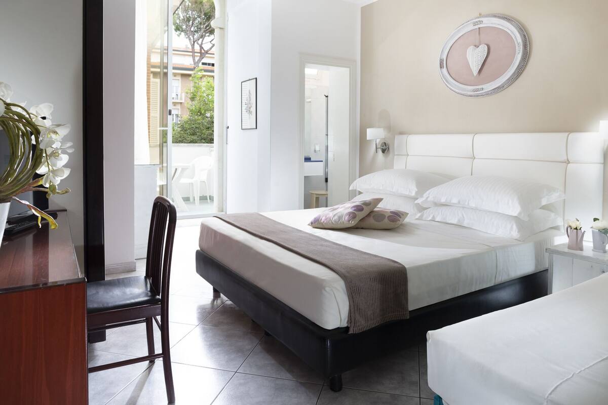 A bedroom with a bed, a chair, a desk, and a window.