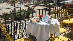 Una mesa con mantel blanco, sillas amarillas y una vista a la playa y sombrillas al fondo.