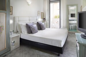 A bedroom with a bed, bedside tables, a dresser, a television, and a bathroom visible through an open door. - Hotel Orizzonte (Bellaria-Igea Marina)