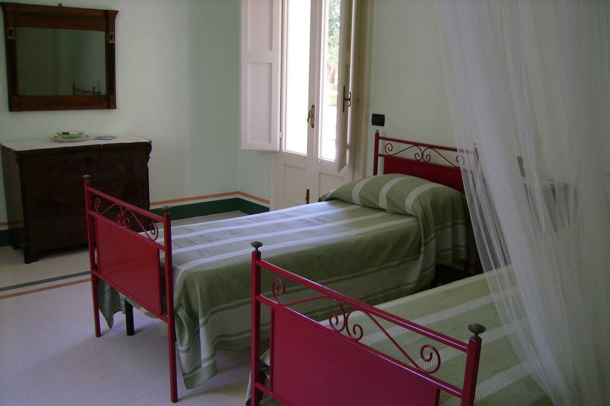 Une chambre avec deux lits simples, une commode et un miroir au mur.