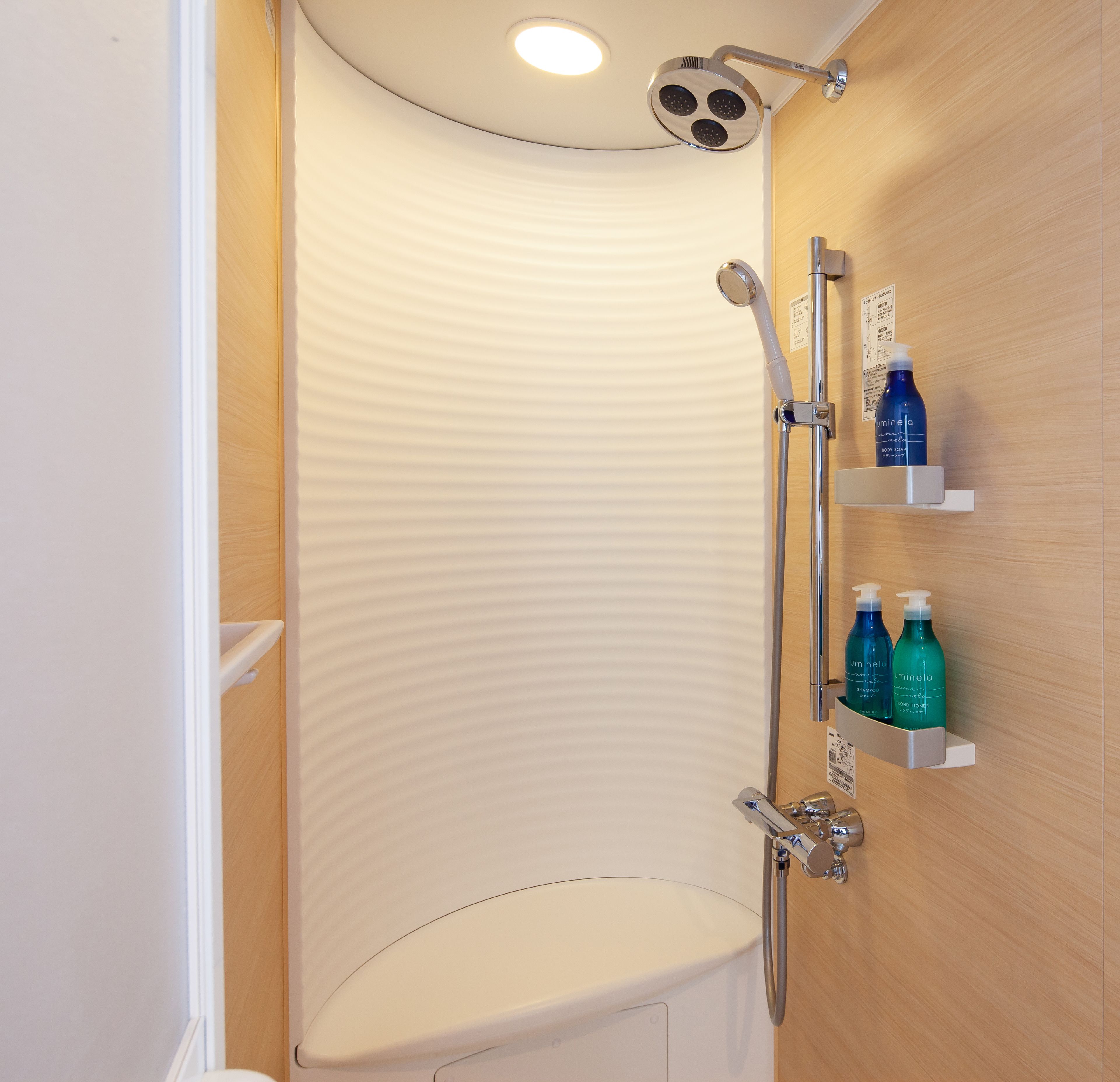 A modern bathroom with a shower, toilet, and built-in shelves holding toiletries.